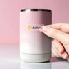 A hand holds a pink tumbler with a yellow name sticker on it.