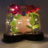 Zwei Glasvasen mit künstlichen roten und rosa Rosen, beleuchtet durch LED-Lichter.