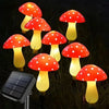 Six solar mushroom garden lights with red caps and yellow glow illuminating grass.