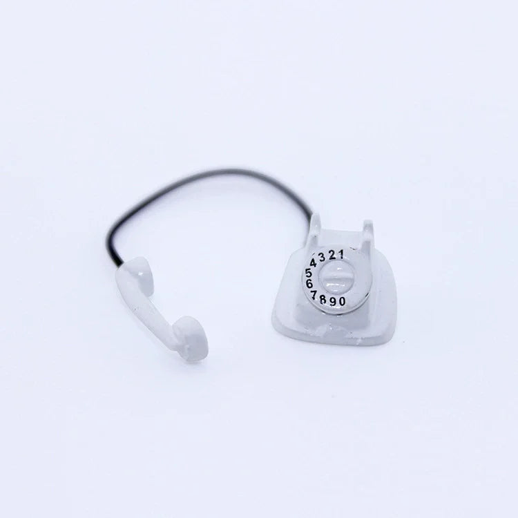 A clear plastic vintage rotary desk phone miniature with a black cord and receiver.