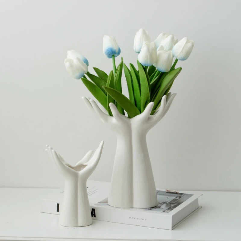 White ceramic hand vase holding a bouquet of blue and white tulips