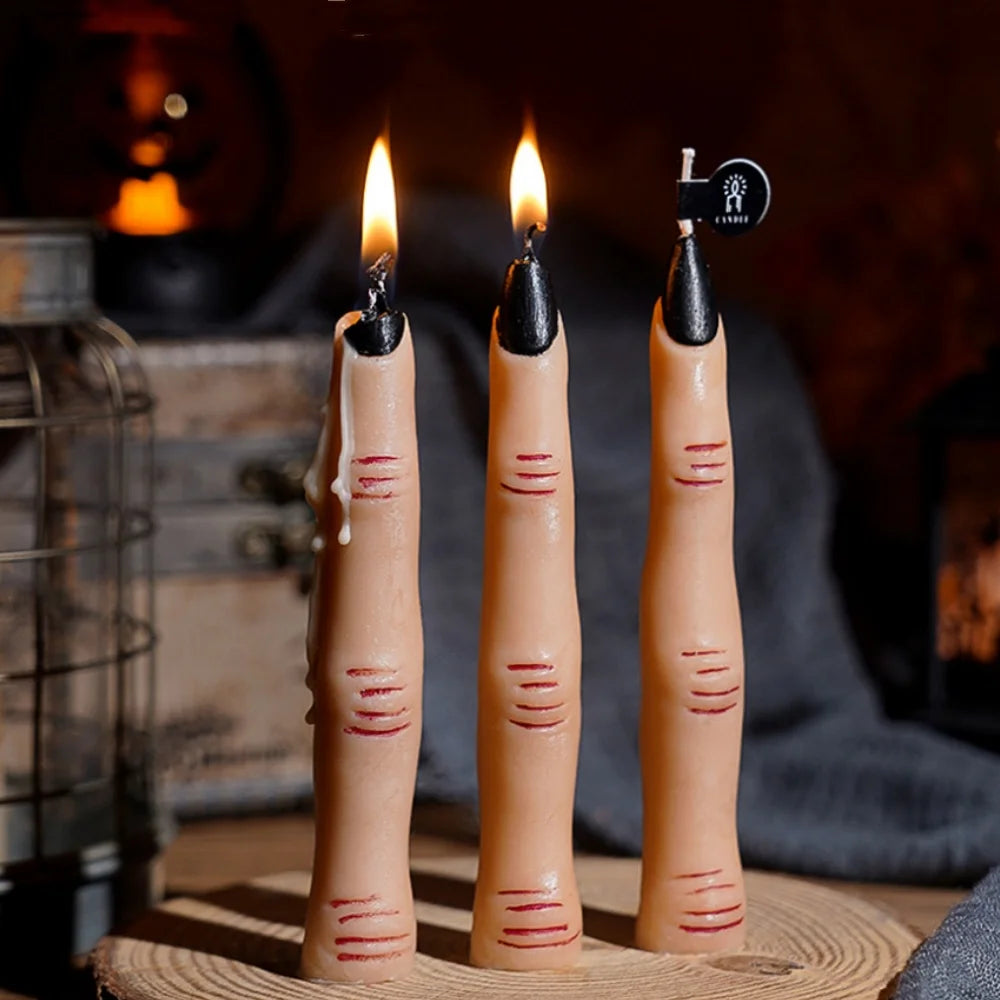 Three tall candles with black wax and lit flames stand on a woven mat in a dark setting.