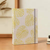 Álbum de scrapbooking de tela beige claro con un patrón repetitivo de contornos de hojas verde amarillentas.