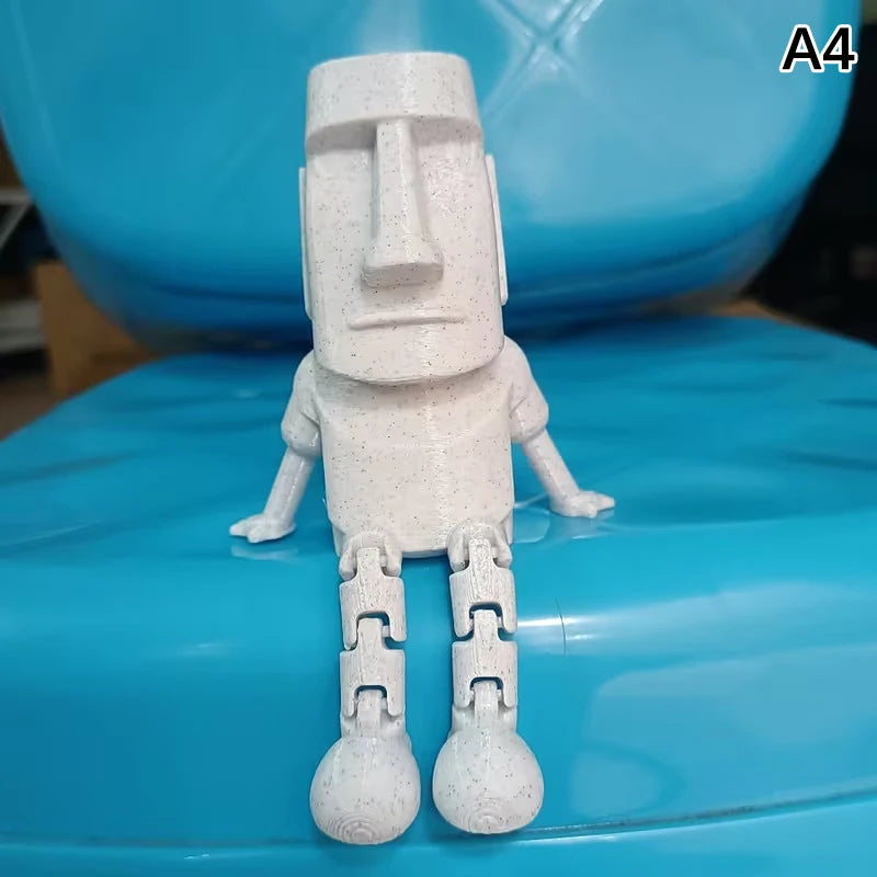 A white 3D printed Moai statue figurine with movable joints displayed on a blue surface.