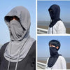 A person wearing a gray breathable full head UV protection mask in an outdoor setting.