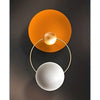 Abstract wall art featuring two concentric circles, one orange and one silver, against a dark gray background.