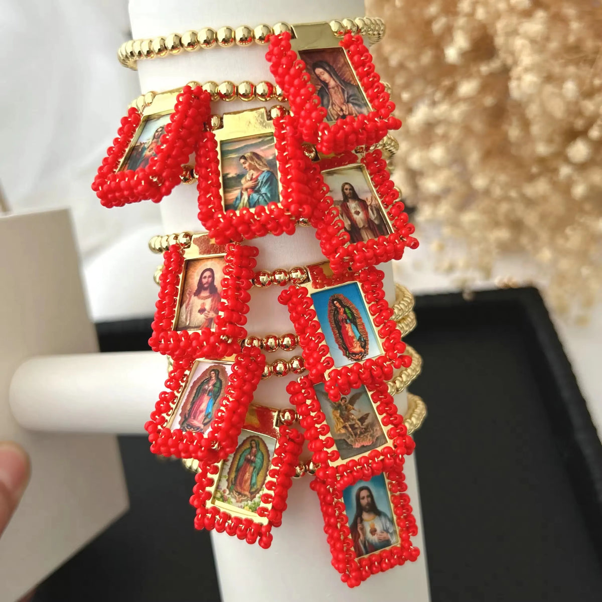 Handmade gold-plated charm bracelet featuring small religious images set in red beaded strands