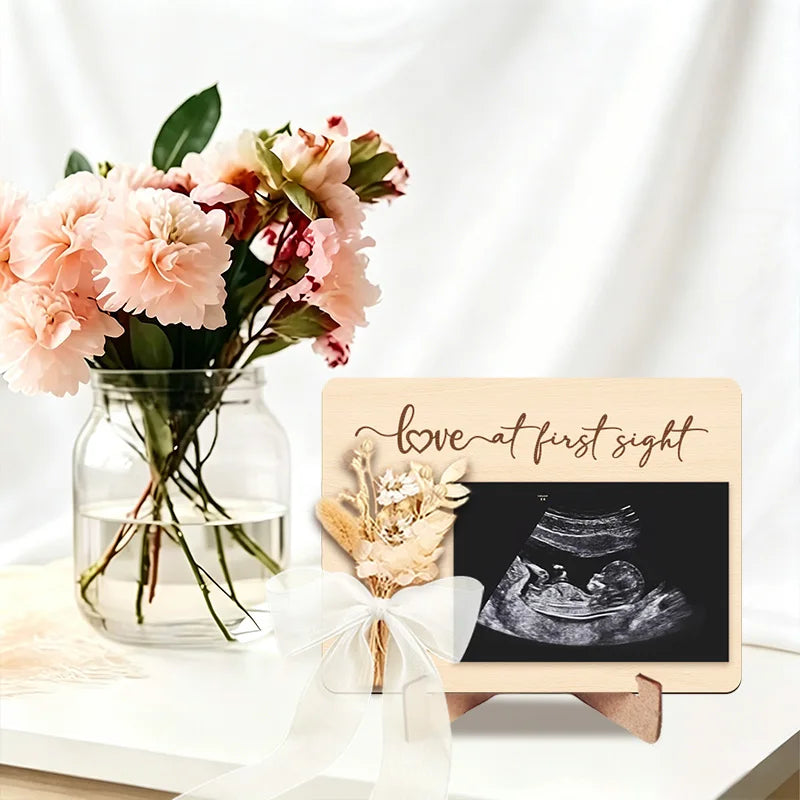 Wooden ultrasound photo frame with a black screen and a white ribbon for a pregnancy announcement
