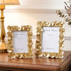 Two gold-framed photo frames with white mats and ginkgo leaf accents resting on a wooden surface.