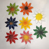 A set of nine metal flower wall decorations in various shades of orange, yellow, green, and blue.
