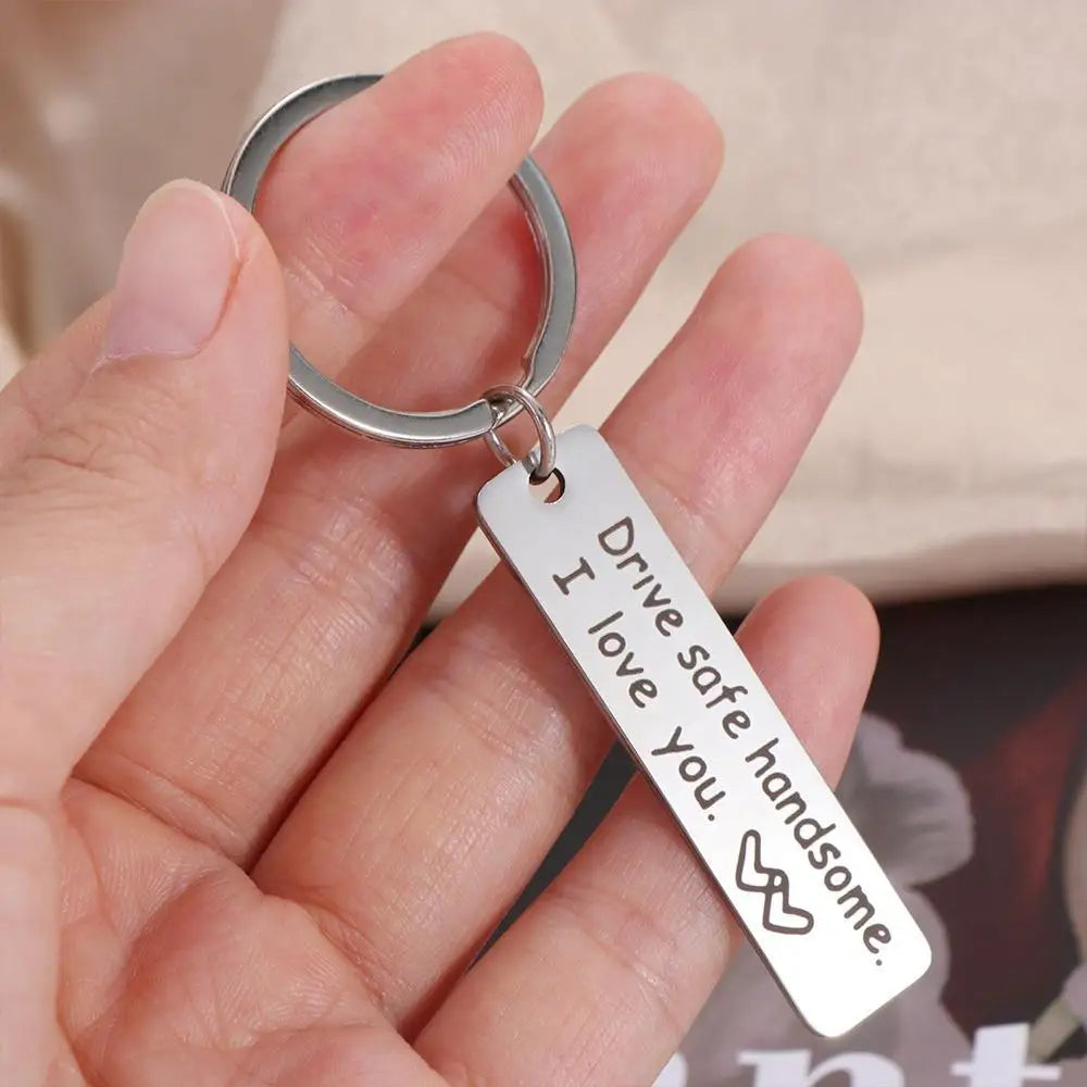 A hand holds an engraved stainless steel keychain with the message I drive safe I love you.
