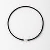 A black string bracelet with a gold plated clasp laid flat on a white background.