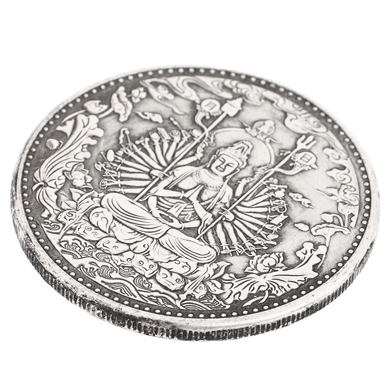 A detailed silver coin featuring a depiction of a meditating Buddha surrounded by foliage and decorative borders.
