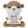 A brown crocheted animal doll with a white face and a card that reads Sister I love you like no otter