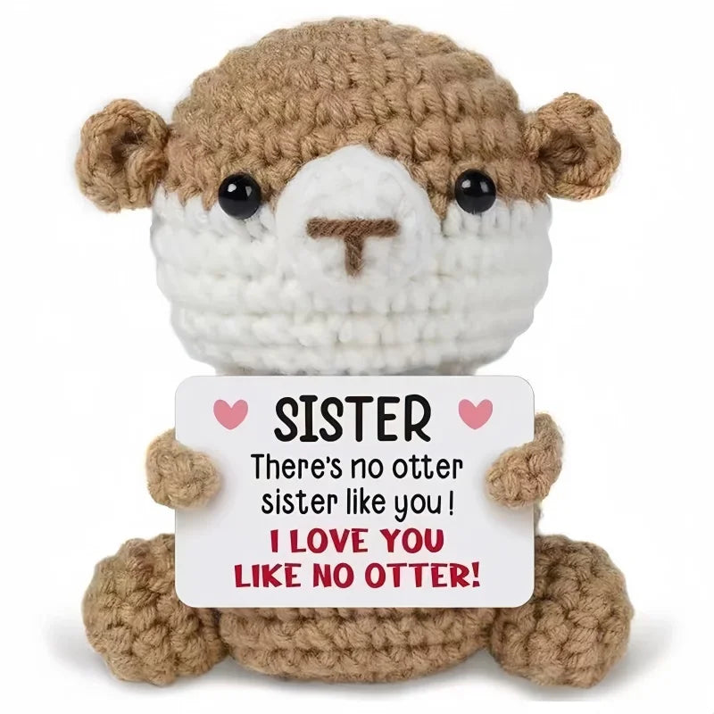 A brown crocheted animal doll with a white face and a card that reads Sister I love you like no otter