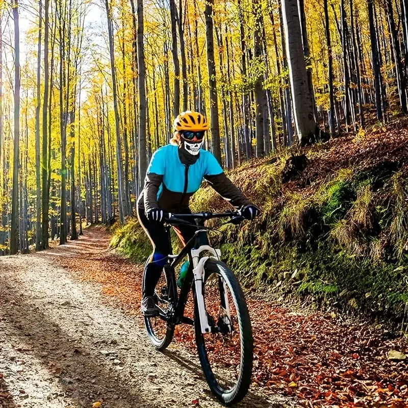 Une personne portant un casque et un masque jaunes fait du vélo sur un sentier de terre dans une forêt d'automne.