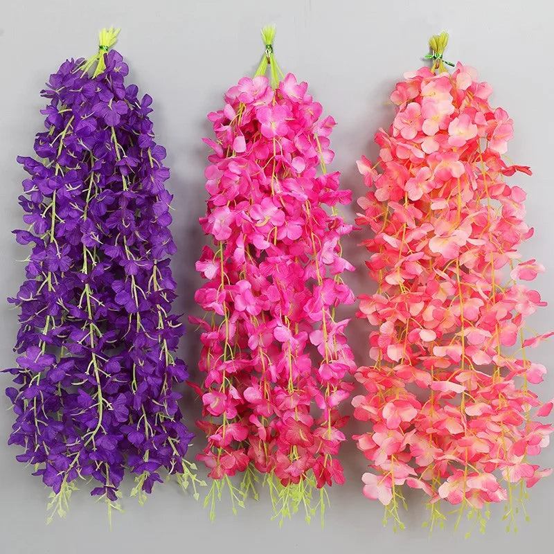 Three vertical garlands of artificial wisteria flowers in purple, pink, and orange hues