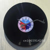 A black vinyl record wall clock with a white face and a blue and red center design.