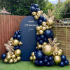 A balloon garland arch featuring navy blue and gold metallic balloons set against a dark blue backdrop.
