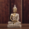 A golden Buddha statue handcrafted from resin sitting in meditation pose on a wooden surface.