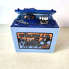 A blue resin piggy bank shaped like Godzilla featuring a detailed figure and an orange label.