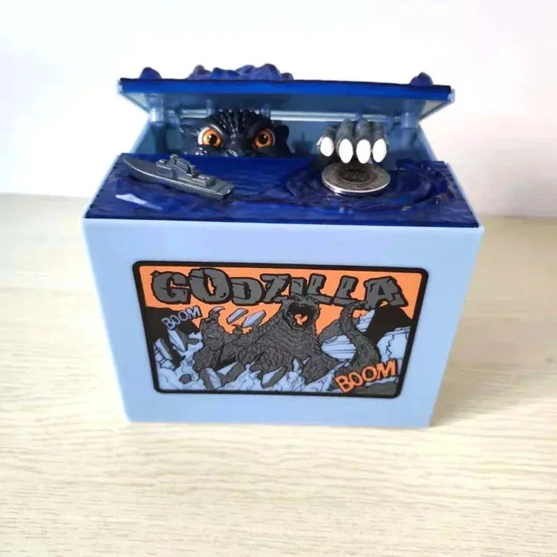 A blue resin piggy bank shaped like Godzilla featuring a detailed figure and an orange label.