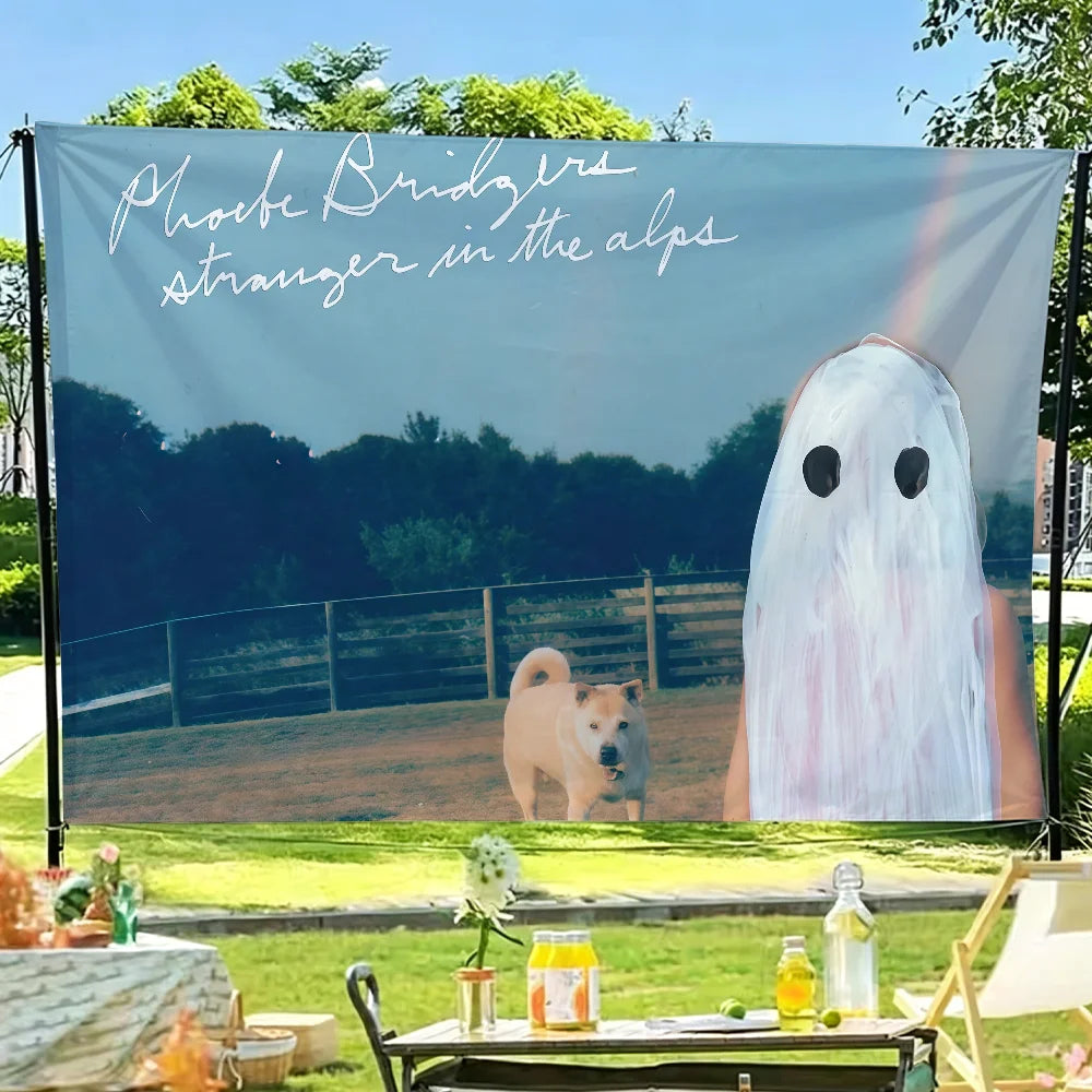 A tapestry featuring Phoebe Bridgers album art, depicting a ghostly figure in the Alps, displayed outdoors.