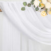 White sheer tulle draping fabric with green leaves and yellow roses used as a wedding arch backdrop.
