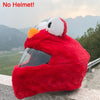 A bright red cartoon plush helmet cover for a full-face motorcycle helmet is displayed outdoors.
