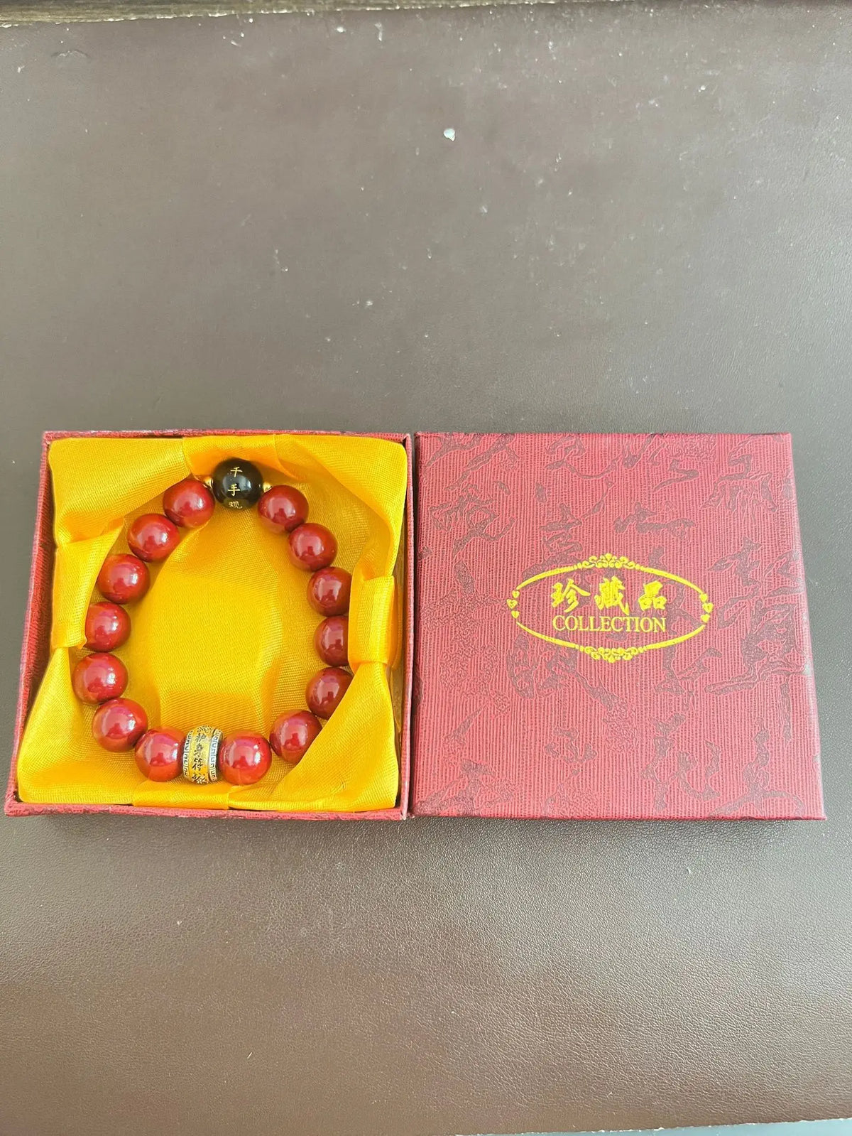 A collection of natural cinnabar stone zodiac bracelets displayed in yellow and pink boxes.