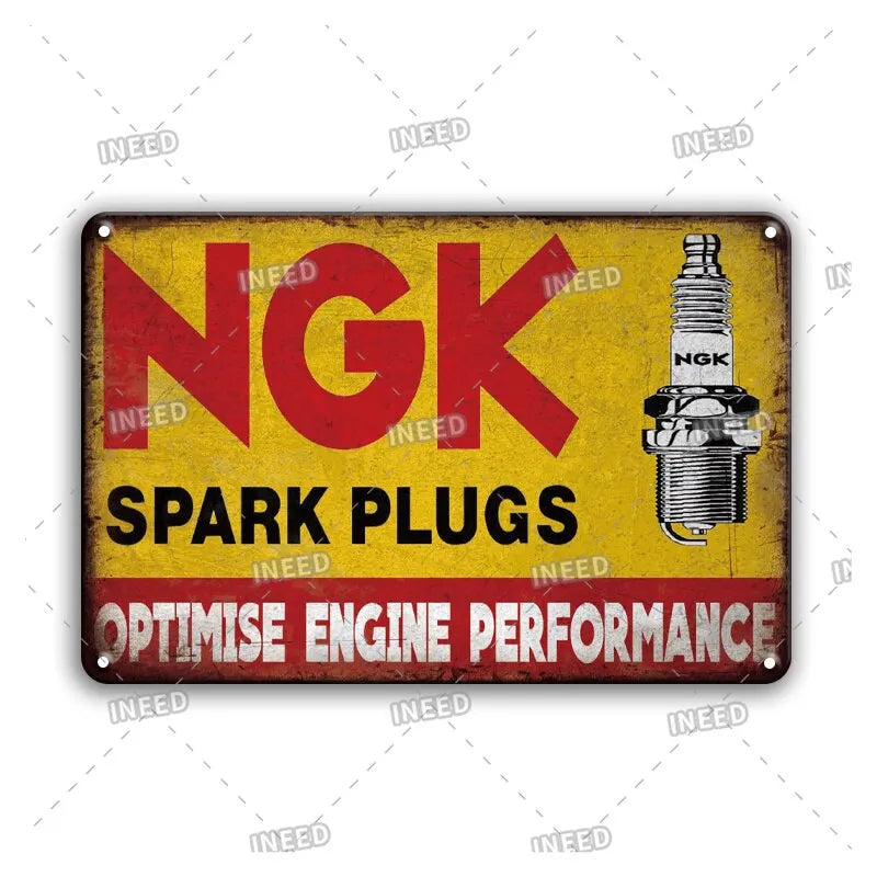 Vintage metal garage sign with red and yellow text advertising spark plugs and engine performance optimization