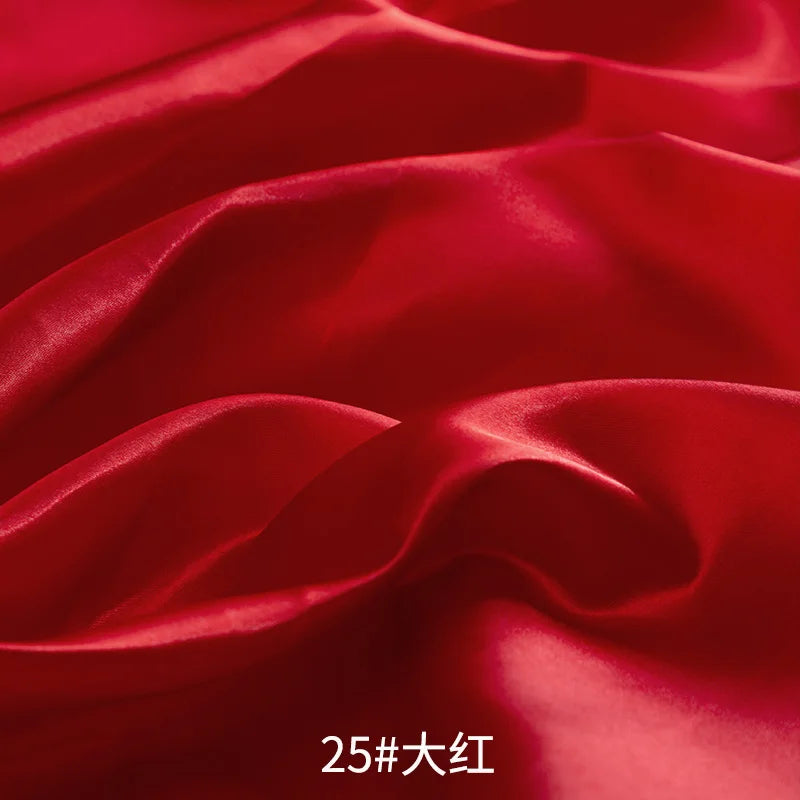 Close-up of rich red satin fabric draped and folded to show texture and sheen.