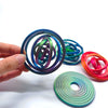 Hand holding a colorful rotating ball spinner fidget toy with various colored rings and a green disc.