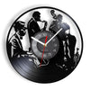 A black silhouette of musicians playing instruments is displayed on a vintage vinyl record wall clock.