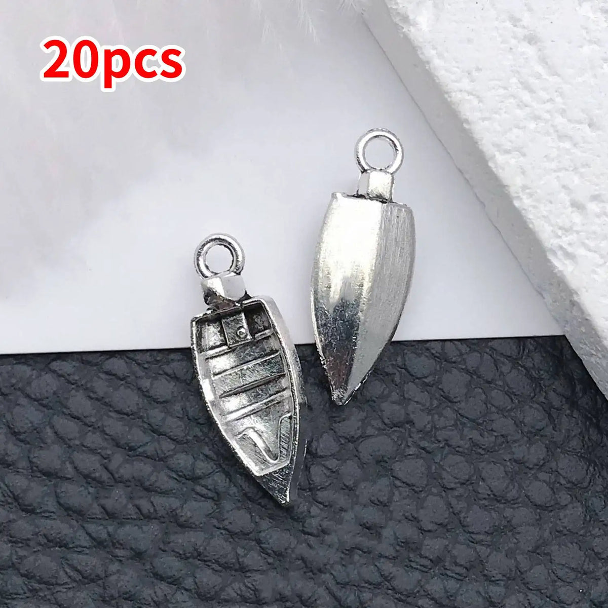 A set of 20 silver vintage ship anchor charms for jewelry making displayed on a dark surface.