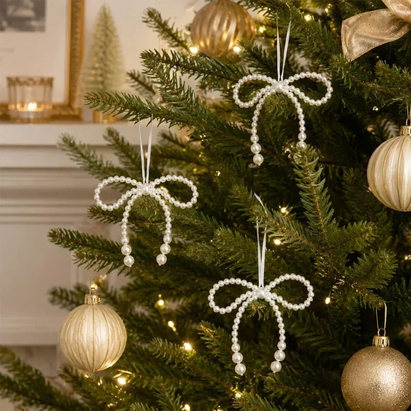 Elegant pearl bow Christmas tree ornaments hanging on a green fir branch.