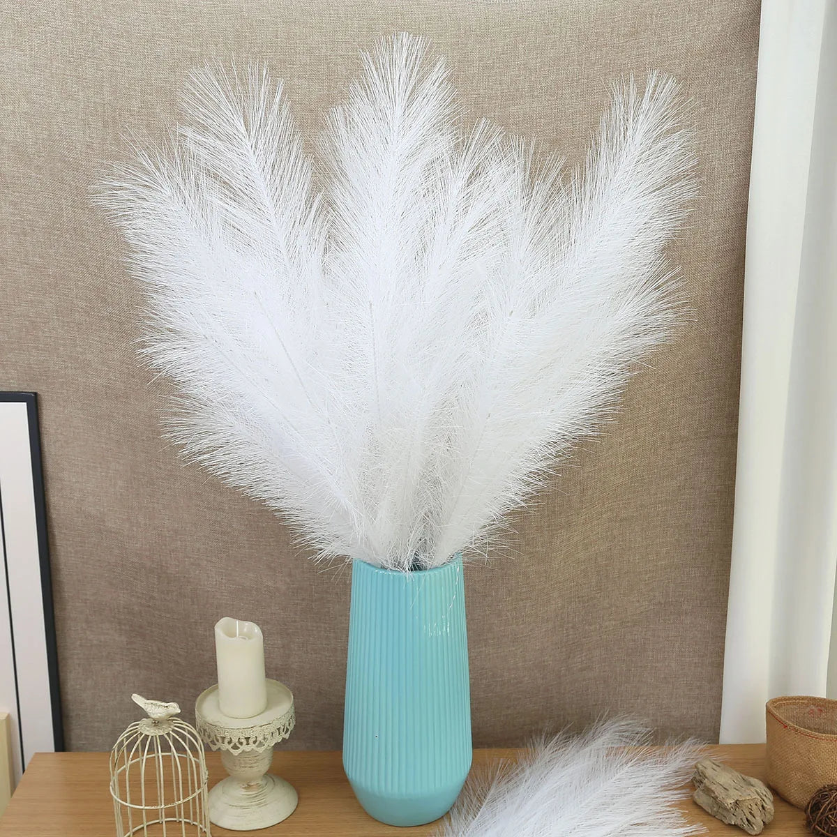 A tall vase filled with white artificial pampas grass used as boho home decor