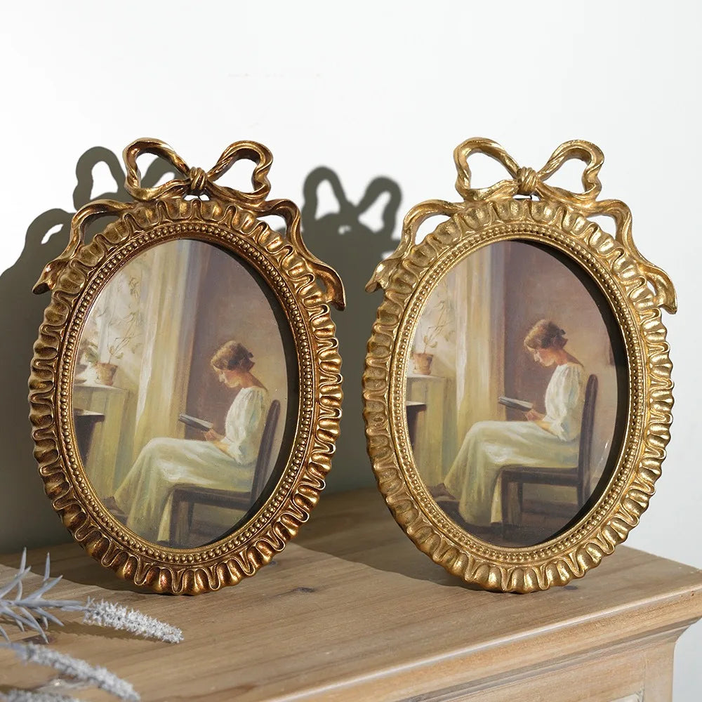 A pair of ornate gold-framed picture frames featuring classical portrait paintings.