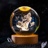 A clear crystal ball with a golden top showing a silhouette of a figure against a starry background.