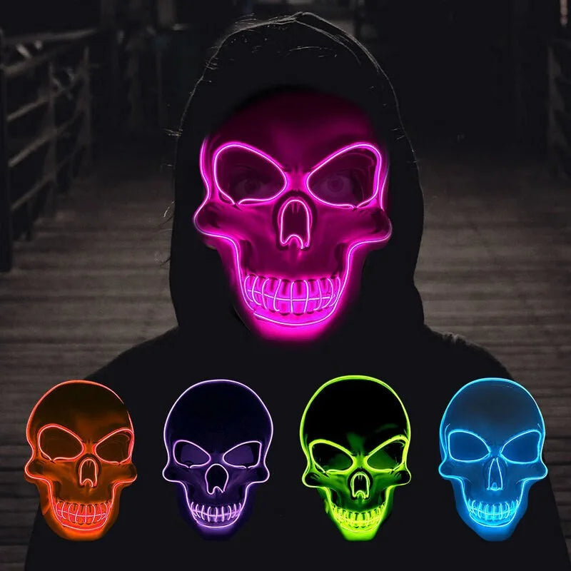 A person wearing a black hoodie with a glowing neon pink skull mask and four other colored LED glow skulls.
