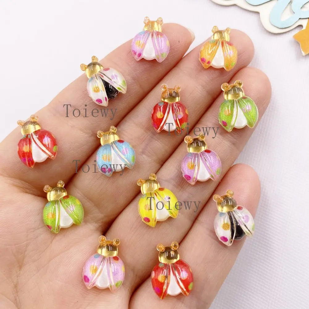 Hand holding several colorful resin beetle rhinestone appliques for DIY crafts
