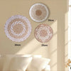 Three round boho straw wall hangings of varying sizes are displayed against a light beige wall.