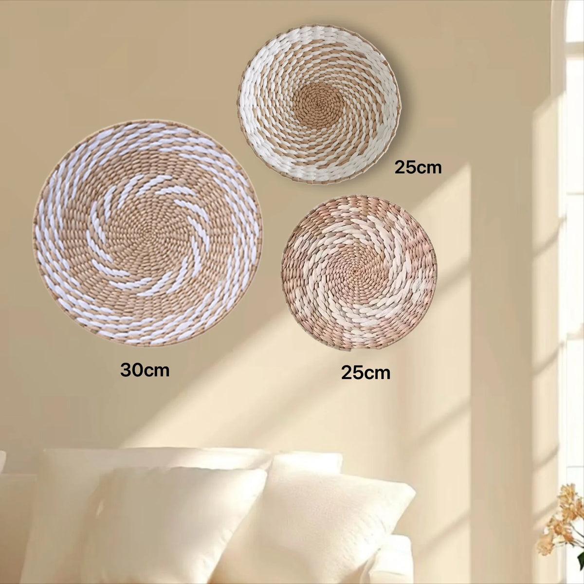Three round boho straw wall hangings of varying sizes are displayed against a light beige wall.
