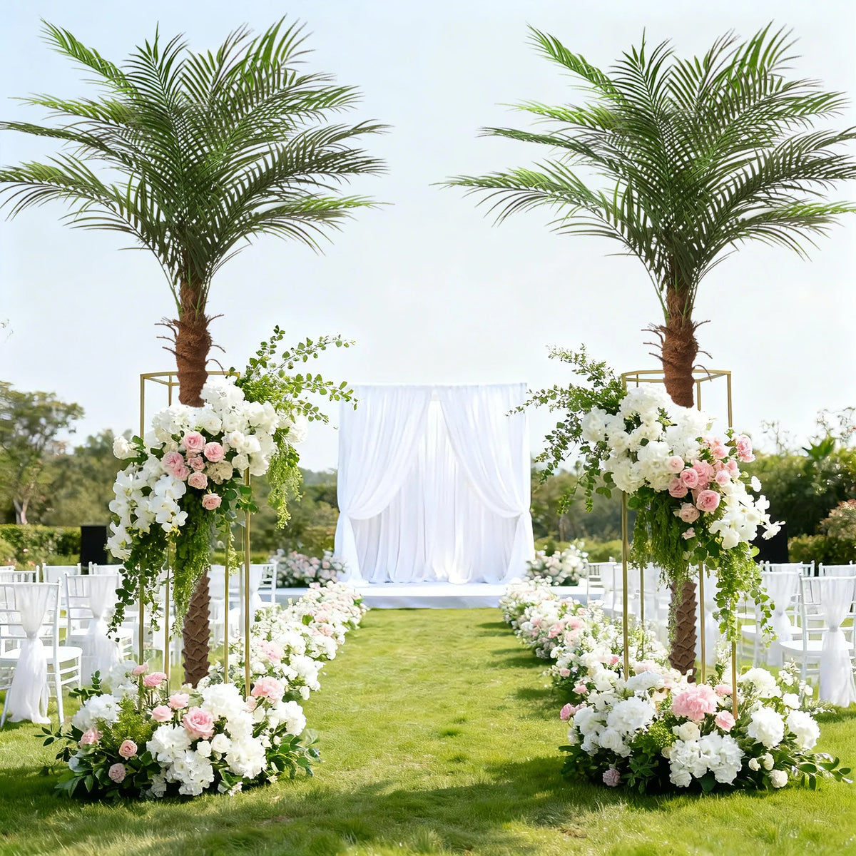A garden aisle decorated with white chairs and floral arrangements flanked by artificial golden palm trees.