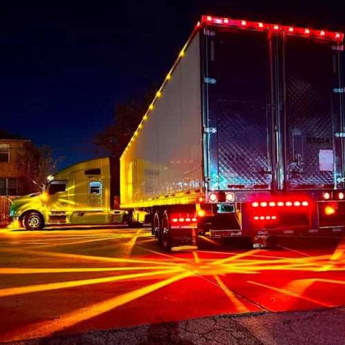 A large semi-truck with bright LED side marker lights driving on a road at night.
