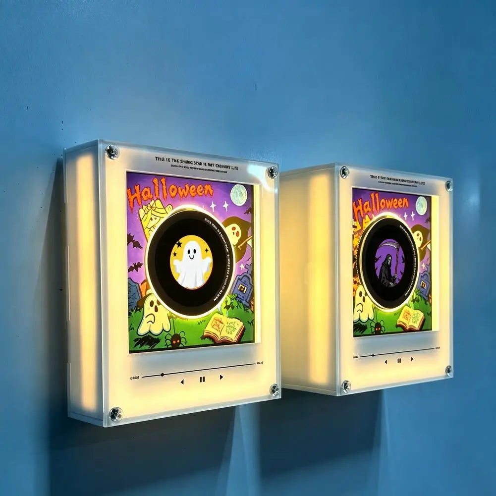 A pair of illuminated magnetic vinyl record night lights with Halloween themed artwork mounted on a wall.
