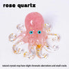 A pink rose quartz crystal octopus statue with translucent arms and spiral tentacles.