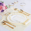 A set of gold disposable cutlery including forks, spoons, and knives arranged on a light fabric with clear glass cups.