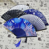 A collection of elegant vintage Chinese folding hand fans in various shades of blue and black displayed on a light patterned 