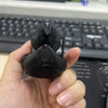 A hand holds a black, 3D printed statue of a Grim Reaper duck for Halloween decor.